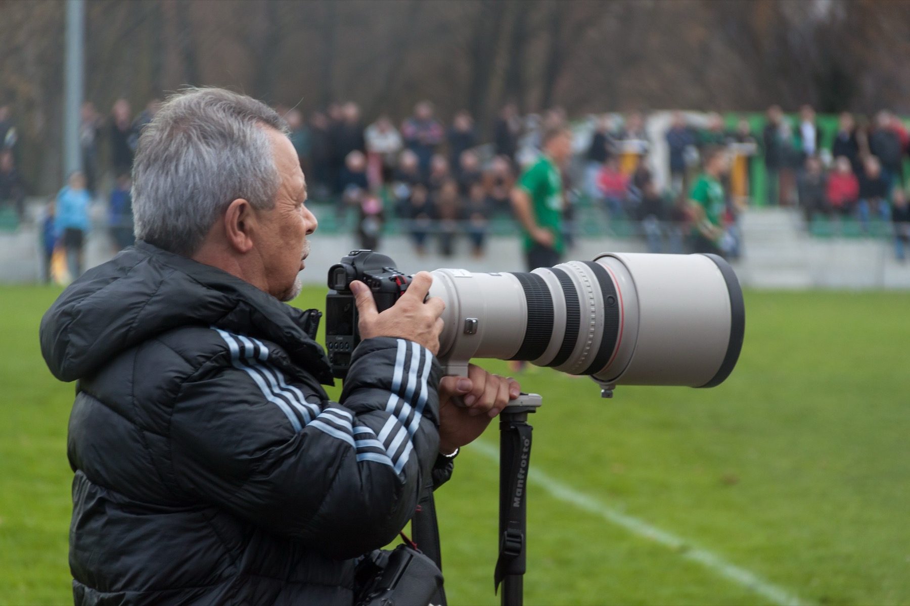 appareil photo équipé d'un long téléobjectif, tenu par un photographe qui vise au loin