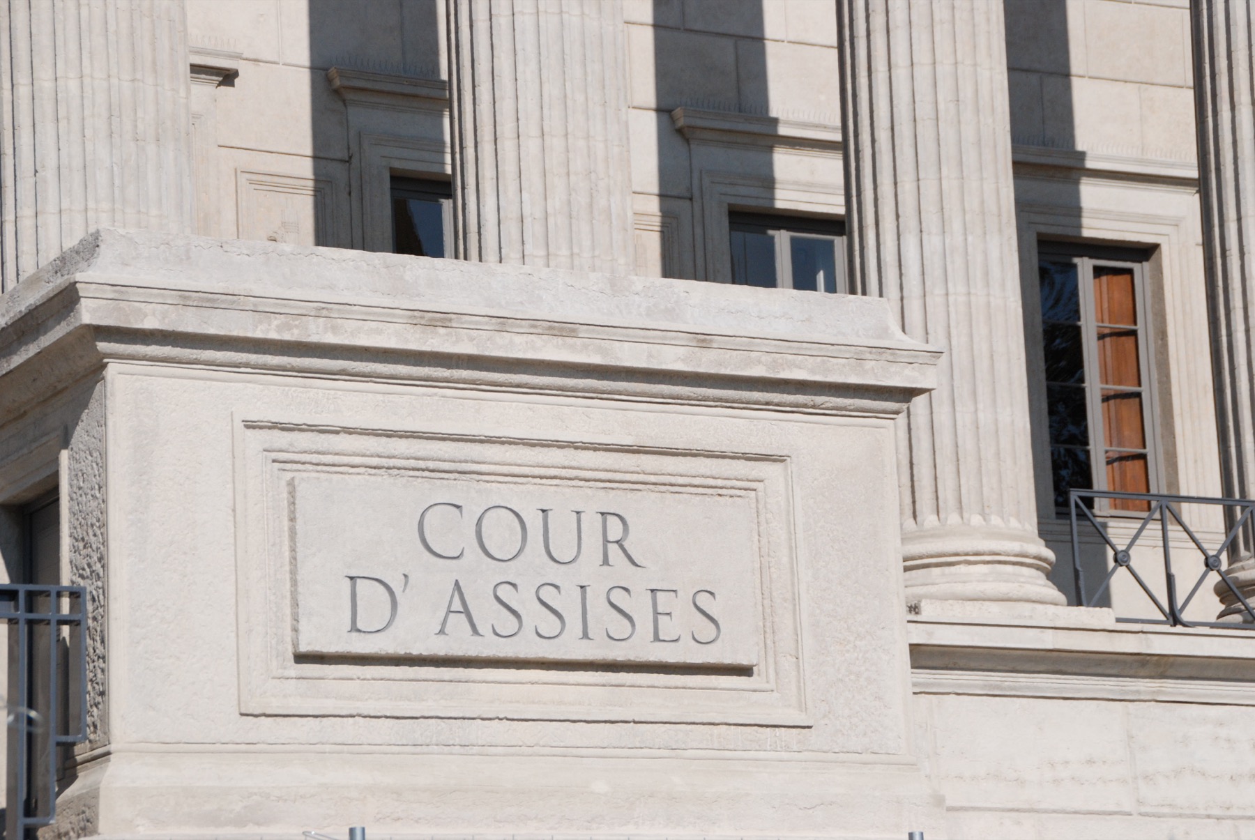 grande salle d'un palais de justice avec ses colonnes, où siège une cour d'assises