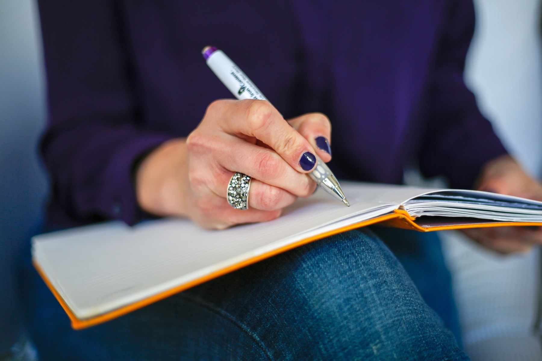 femme écrivant dans un carnet avec un stylo, vue de dessus