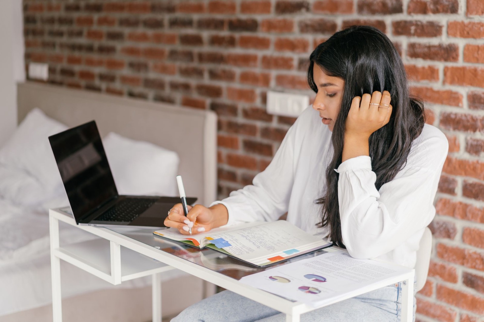 Personne étudiant sur un ordinateur portable avec un carnet de notes et un certificat