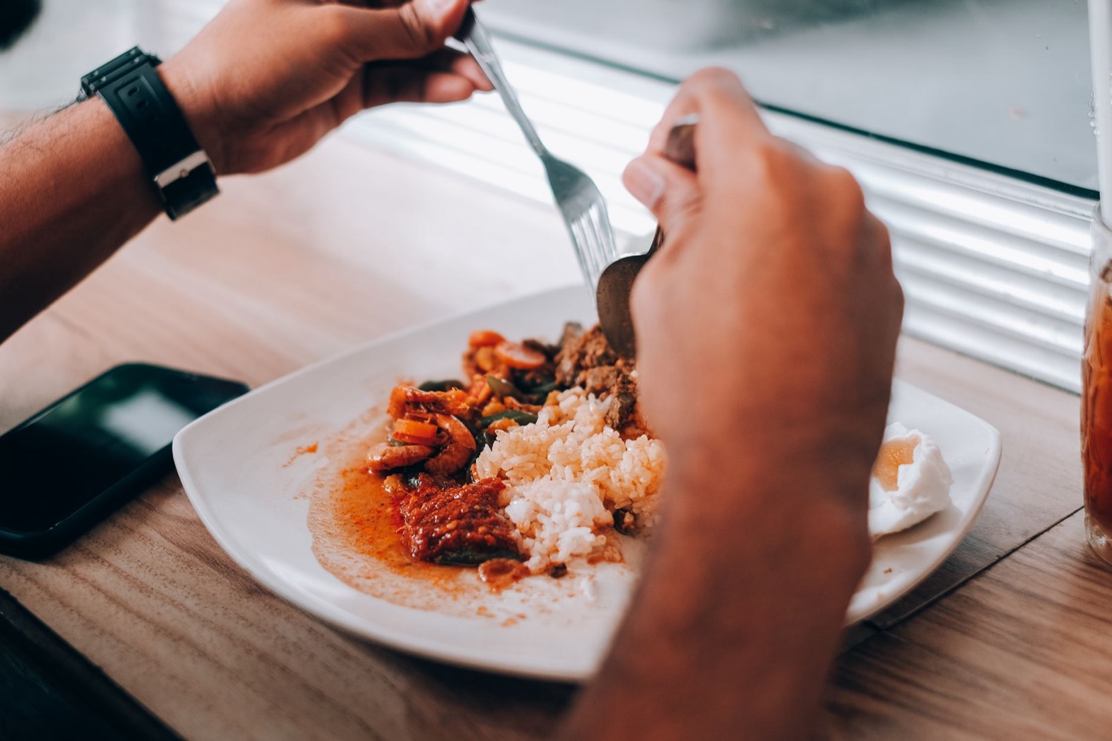 Une personne attablée devant un repas, à côté d'une horloge, illustrant le lien entre horaires de repas et digestion