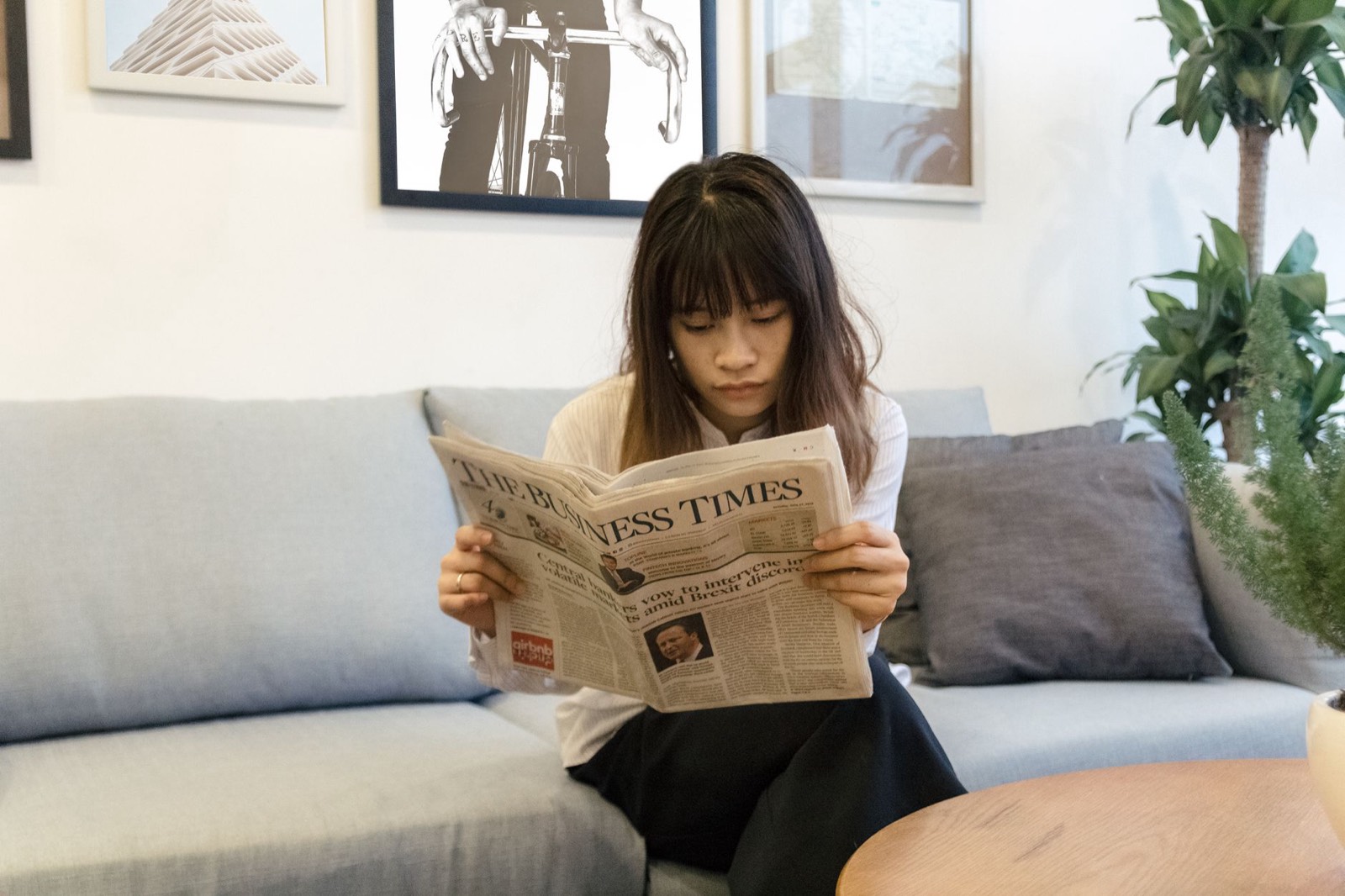 Personne lisant un journal papier dans son salon