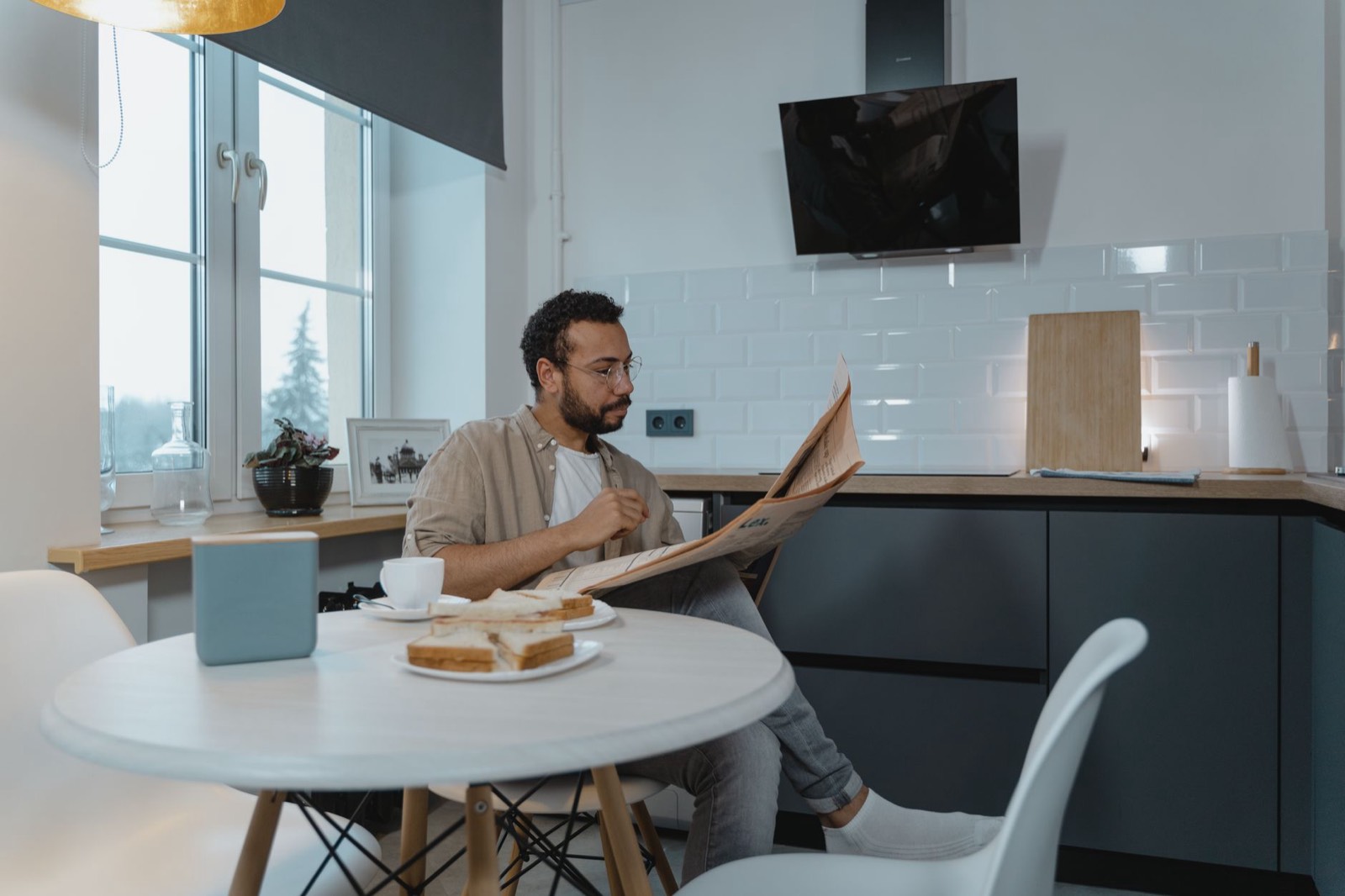Personne lisant un journal papier à table dans sa cuisine